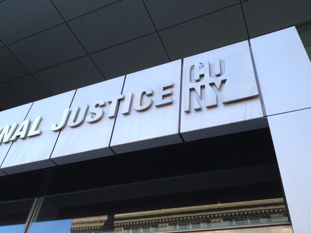 Close-up detail of installed exterior John Jay College building signage with modern typography